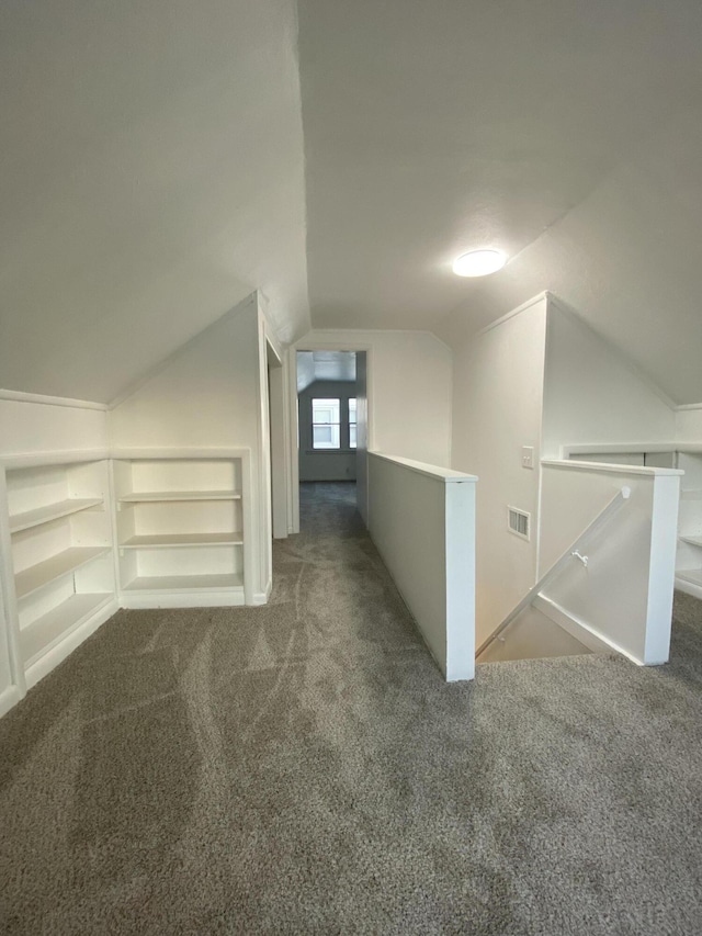 bonus room with dark colored carpet, vaulted ceiling, and built in features