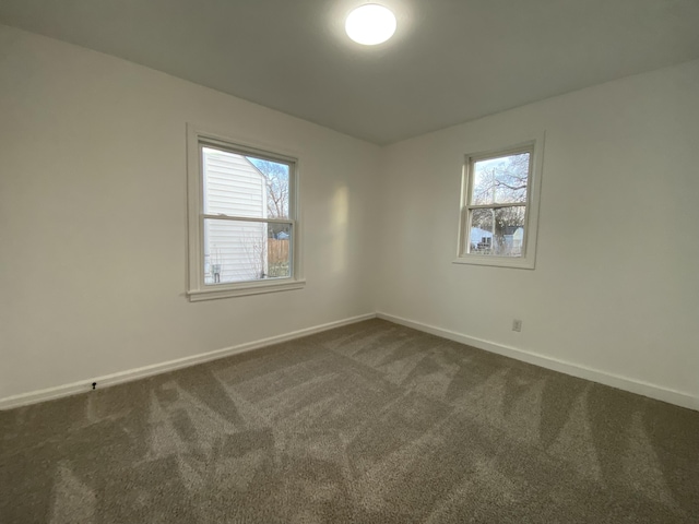 spare room with a healthy amount of sunlight and dark colored carpet