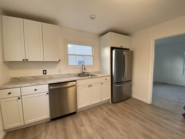 kitchen with stainless steel appliances, white cabinetry, sink, and light wood-type flooring