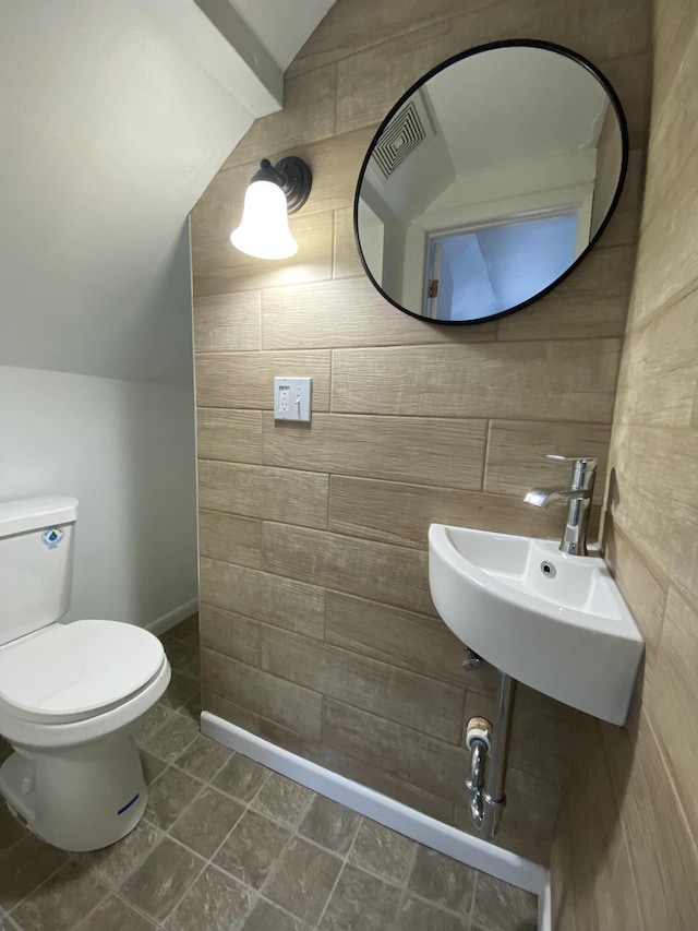 bathroom featuring lofted ceiling, sink, and toilet