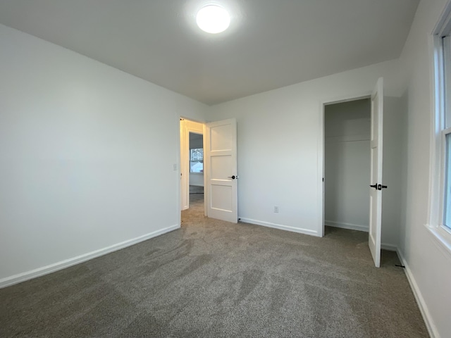 unfurnished bedroom with dark carpet and a closet