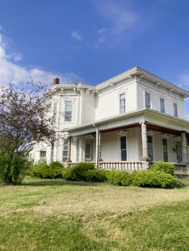 119 E Orchard St, West Manchester, OH 45382 - view of side of property featuring a chimney, covered porch, and a lawn