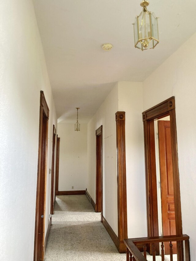 119 E Orchard St, West Manchester, OH 45382 - hallway featuring light colored carpet, a chandelier, and baseboards