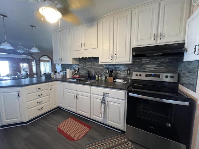 kitchen featuring arched walkways, a peninsula, stainless steel electric range, under cabinet range hood, and a sink