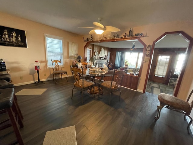 dining room with arched walkways, ceiling fan, wood finished floors, and baseboards