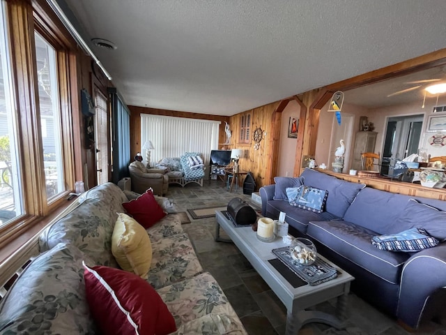 living room featuring a textured ceiling and wooden walls