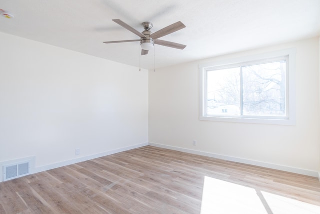 spare room featuring ceiling fan, light wood-style flooring, visible vents, and baseboards