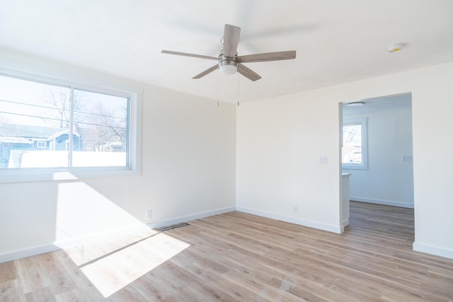 spare room with light wood-type flooring, baseboards, visible vents, and ceiling fan