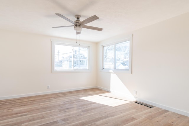 empty room featuring visible vents, light wood-style flooring, and baseboards