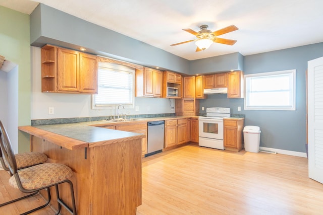 kitchen with white electric range, a peninsula, a sink, dishwasher, and brown cabinetry