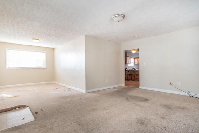 carpeted empty room with a textured ceiling and baseboards