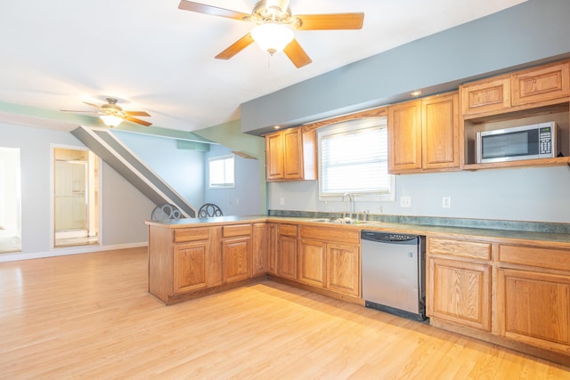 kitchen with light wood finished floors, appliances with stainless steel finishes, brown cabinets, a peninsula, and a sink