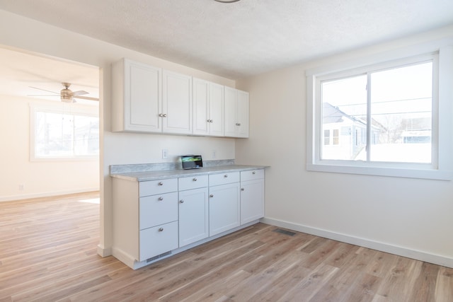 kitchen with a wealth of natural light, light countertops, and white cabinets