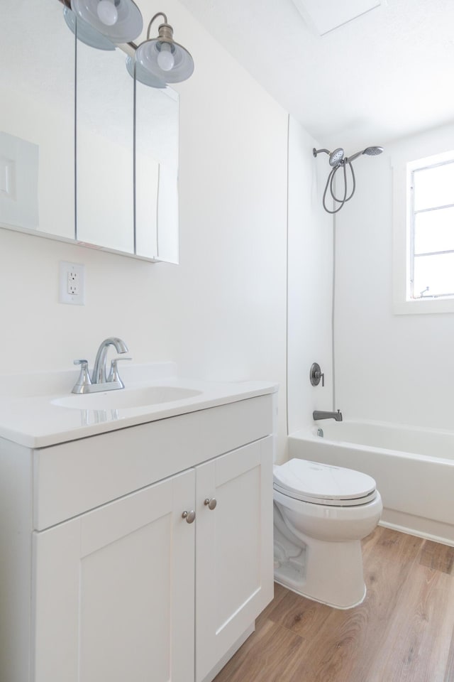 full bath with toilet, shower / bath combination, wood finished floors, and vanity