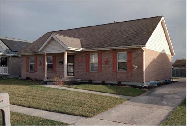 ranch-style home with brick siding, a front lawn, and a shingled roof