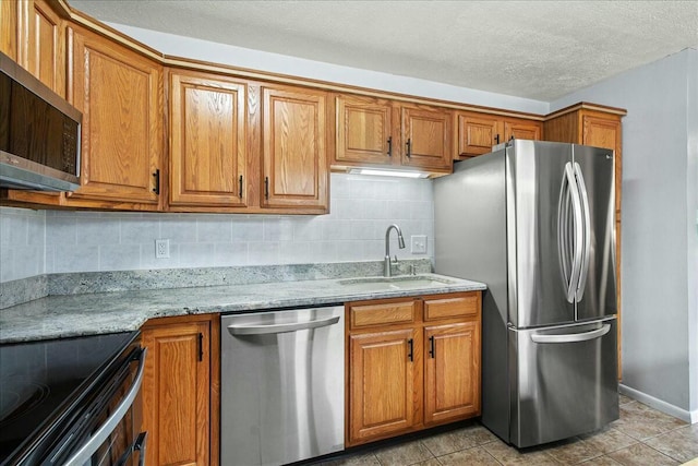 kitchen featuring appliances with stainless steel finishes, brown cabinetry, and a sink