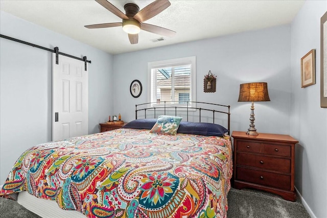 bedroom featuring a barn door, visible vents, baseboards, ceiling fan, and carpet