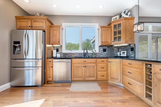 6565 Windjammer Dr, Huntsville, OH 43324 - kitchen with stainless steel appliances, decorative backsplash, glass insert cabinets, recessed lighting, and light wood-style flooring
