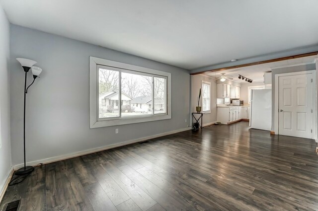 unfurnished living room with dark wood finished floors, baseboards, and visible vents