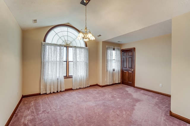 carpeted spare room with vaulted ceiling and a chandelier