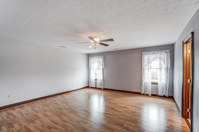 unfurnished room with a textured ceiling, plenty of natural light, ceiling fan, and light wood-type flooring