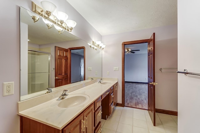 bathroom with tile patterned floors, vanity, a shower with door, and a textured ceiling