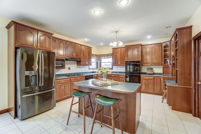 kitchen with light tile patterned flooring, a breakfast bar area, decorative light fixtures, a kitchen island, and black appliances