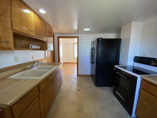 kitchen with a sink, brown cabinets, black appliances, and light countertops