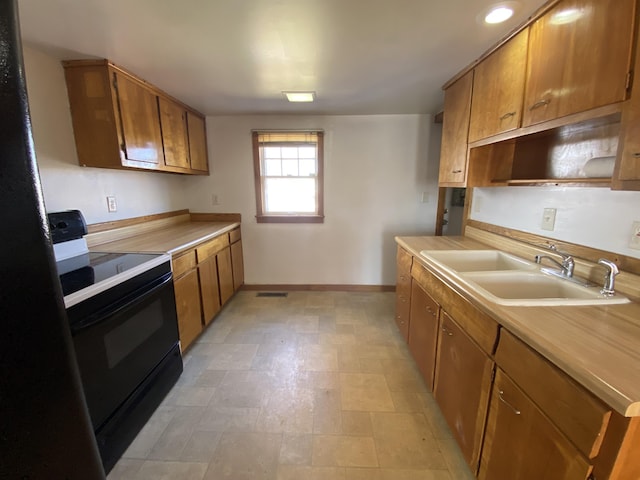 kitchen featuring visible vents, light countertops, brown cabinets, black electric range oven, and a sink