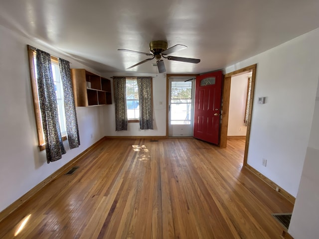 unfurnished living room featuring visible vents, baseboards, and wood-type flooring