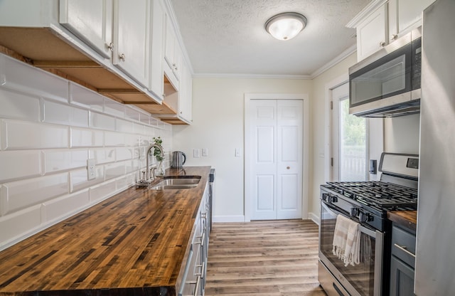 4209 State Route 41, Troy, OH 45373 - kitchen with butcher block counters, appliances with stainless steel finishes, a sink, light wood-type flooring, and ornamental molding