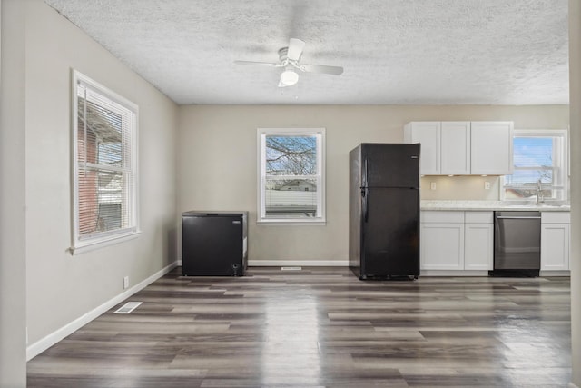 kitchen with dark wood-style flooring, light countertops, stainless steel dishwasher, freestanding refrigerator, and white cabinets