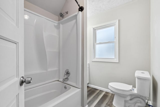 full bathroom featuring a textured ceiling, bathtub / shower combination, toilet, wood finished floors, and baseboards