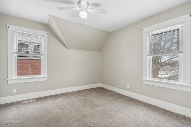 additional living space featuring lofted ceiling, visible vents, carpet flooring, ceiling fan, and baseboards