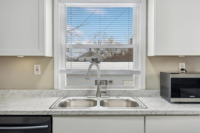 kitchen with appliances with stainless steel finishes, a healthy amount of sunlight, white cabinets, and a sink