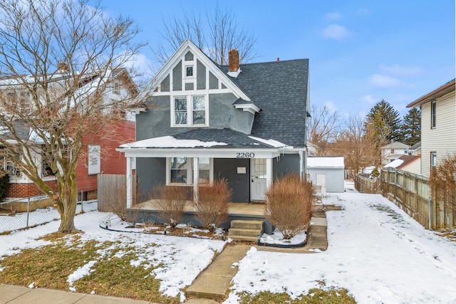 view of front of home featuring a garage, a shingled roof, a chimney, a porch, and stucco siding