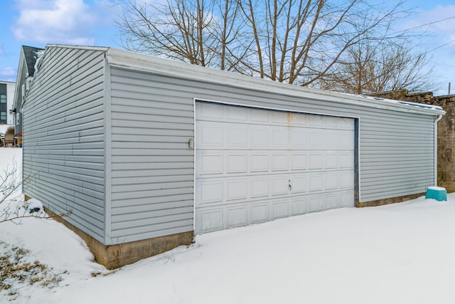 snow covered garage with a detached garage