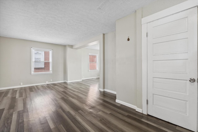 unfurnished room featuring dark wood finished floors, a textured ceiling, and baseboards