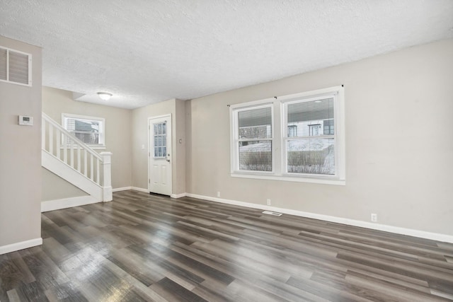 interior space with dark wood-style flooring, visible vents, stairway, and baseboards