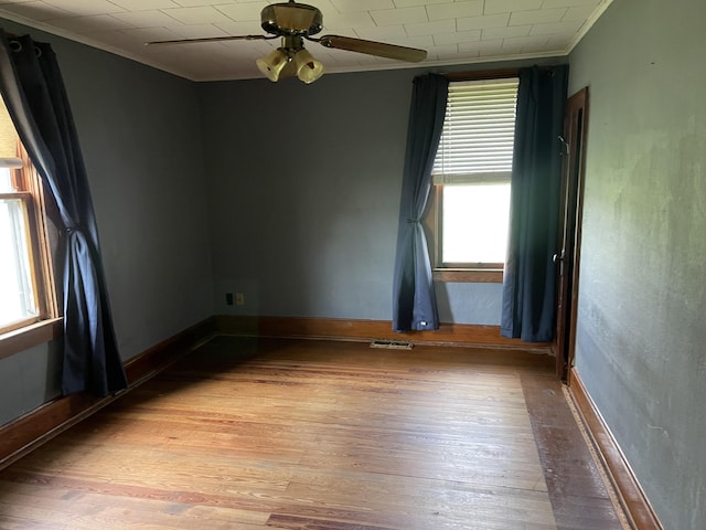 spare room with a wealth of natural light, crown molding, and light wood-style flooring