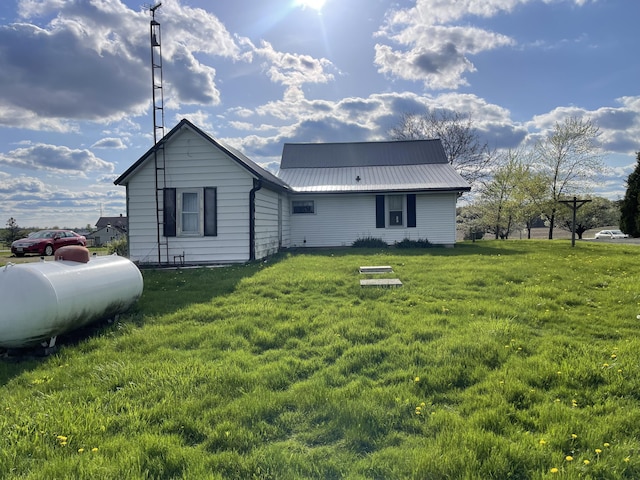 rear view of house featuring metal roof and a yard