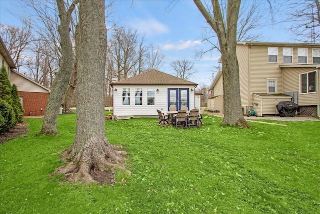 rear view of house with roof with shingles and a yard