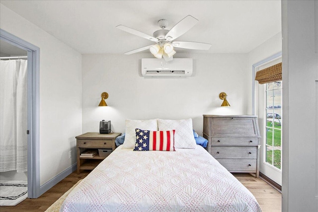 bedroom with ceiling fan, baseboards, wood finished floors, and a wall mounted air conditioner