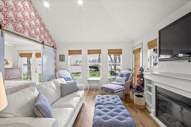 living area with lofted ceiling, light wood-type flooring, and a glass covered fireplace