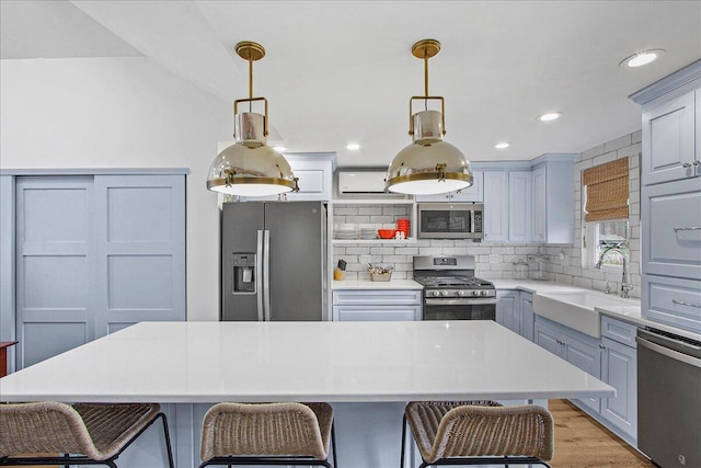 kitchen with stainless steel appliances, a sink, light countertops, a center island, and pendant lighting