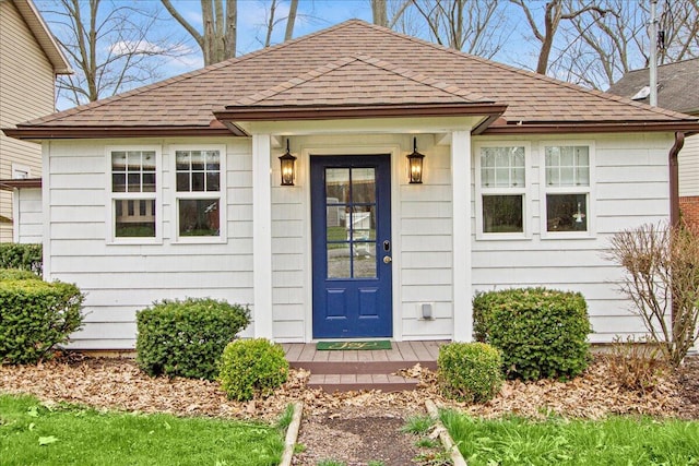 doorway to property with roof with shingles