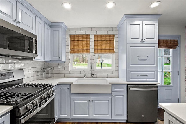 kitchen featuring a sink, backsplash, stainless steel appliances, and light countertops