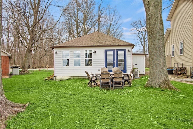 rear view of house featuring a yard, french doors, and roof with shingles