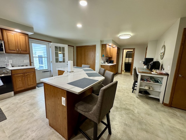 641 Washington St, Versailles, OH 45380 - kitchen featuring stainless steel appliances, a kitchen bar, a center island, brown cabinetry, and decorative backsplash