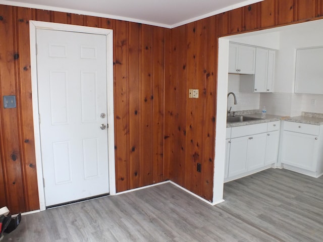 324 E Maplewood Ave, Dayton, OH 45405 - kitchen with white cabinets, light wood-style flooring, a sink, wooden walls, and light countertops